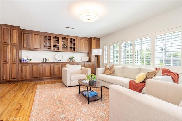 living room with light wood-style flooring and ornamental molding
