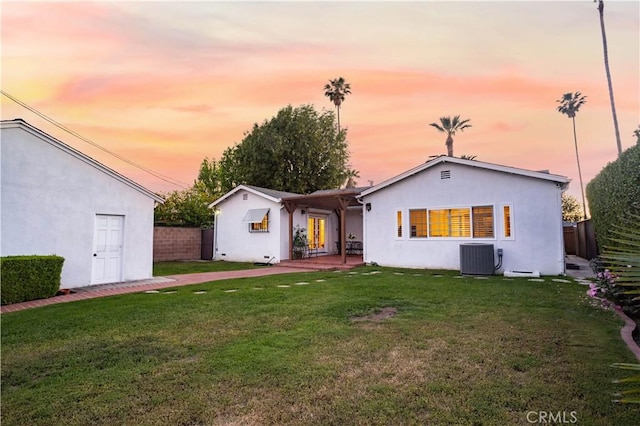 back of property at dusk with stucco siding and central AC