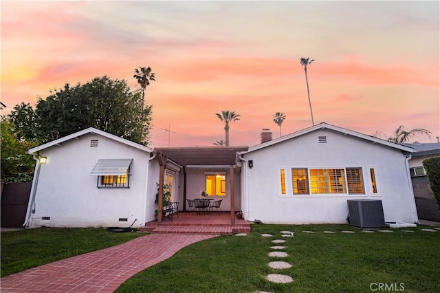 back of house at dusk with central AC unit, a yard, a patio, and crawl space