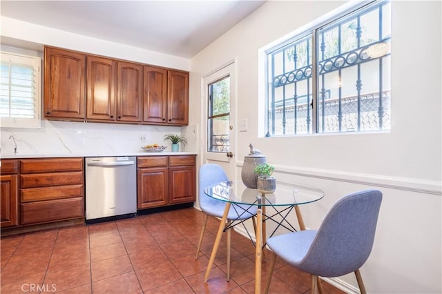 kitchen with dishwasher, light countertops, brown cabinetry, and tasteful backsplash