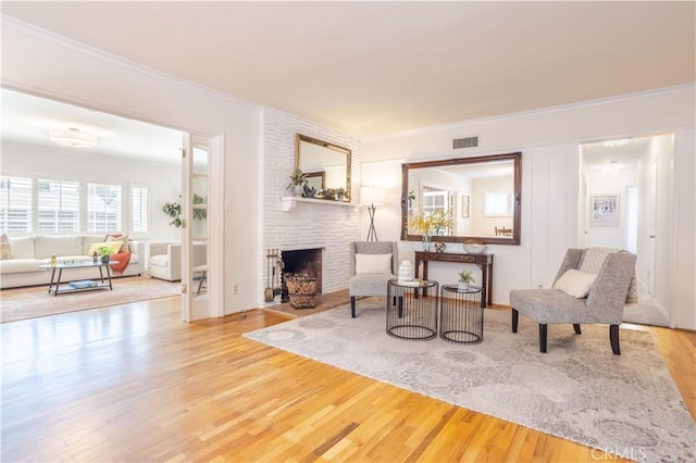 living room with wood finished floors, ornamental molding, and a fireplace
