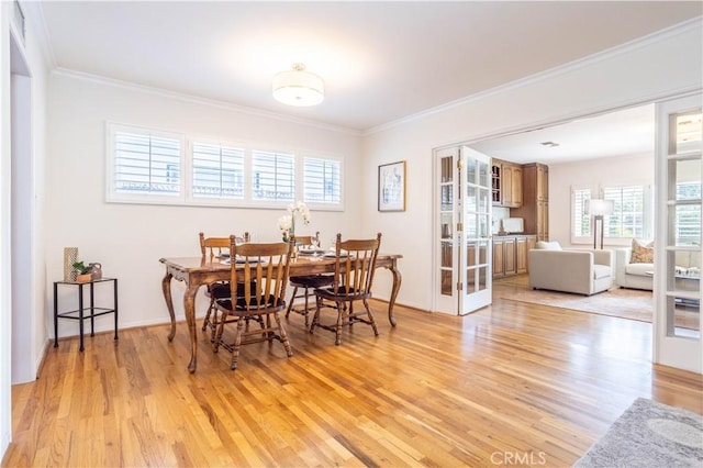 dining area with light wood-style flooring, ornamental molding, and plenty of natural light