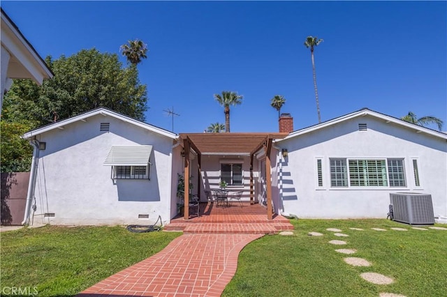 view of front of house with central air condition unit, a chimney, stucco siding, and a front lawn