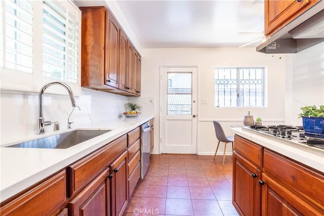 kitchen featuring a sink, under cabinet range hood, light countertops, and stainless steel dishwasher