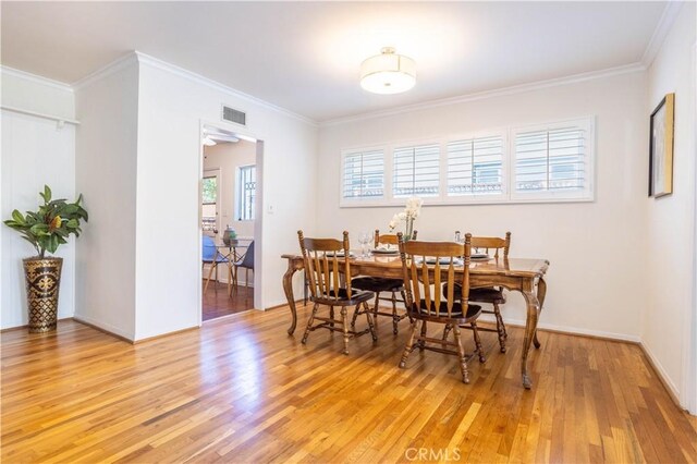 dining space featuring light wood-style flooring and crown molding