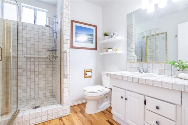bathroom with wood finished floors, a stall shower, toilet, and vanity