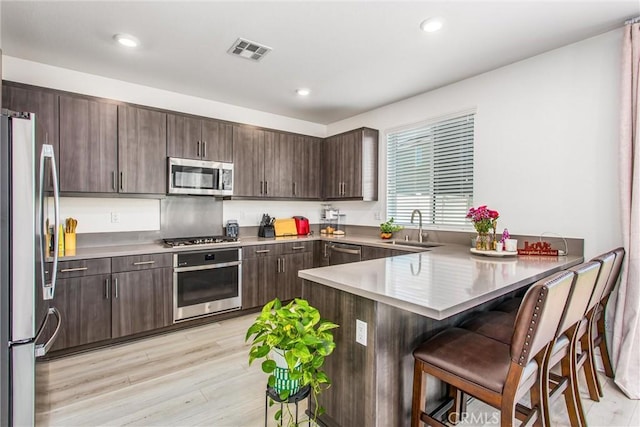 2335 Powell Dr, Rialto, CA 92377 - kitchen featuring stainless steel appliances, a sink, dark brown cabinets, a peninsula, and a breakfast bar