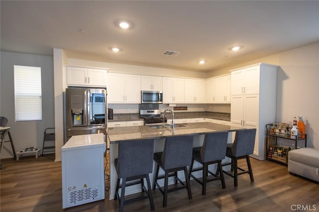1810 Park Place Ln, Riverside, CA 92501 - kitchen featuring appliances with stainless steel finishes, white cabinets, an island with sink, a breakfast bar area, and recessed lighting