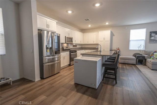 1810 Park Place Ln, Riverside, CA 92501 - kitchen with appliances with stainless steel finishes, a sink, white cabinets, a kitchen bar, and dark wood-style floors