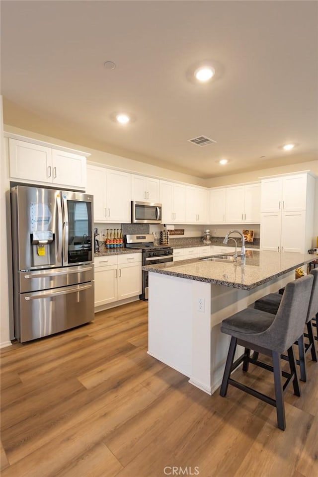 1810 Park Place Ln, Riverside, CA 92501 - kitchen featuring appliances with stainless steel finishes, a sink, white cabinetry, a kitchen breakfast bar, and recessed lighting