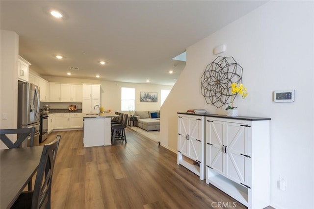 1810 Park Place Ln, Riverside, CA 92501 - kitchen with stainless steel fridge, open floor plan, a breakfast bar, dark countertops, and dark wood-style flooring