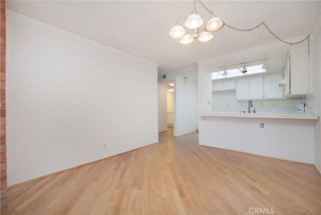 6523 E Camino Unit 2, Anaheim, CA 92807 - unfurnished living room with light wood-type flooring, a chandelier, a sink, and ornamental molding