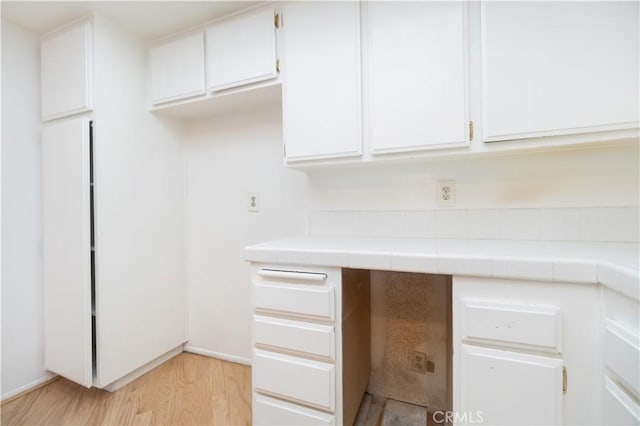 6523 E Camino Unit 2, Anaheim, CA 92807 - kitchen with tile counters, white cabinets, light wood-style flooring, and baseboards