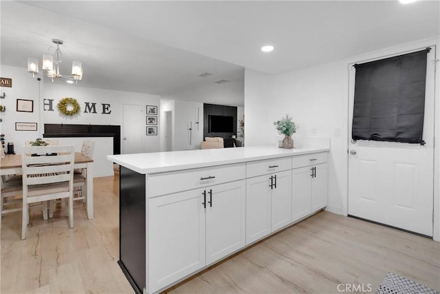 21046 Lone Eagle Rd, Apple Valley, CA 92308 - kitchen with a peninsula, light wood finished floors, light countertops, a chandelier, and white cabinets