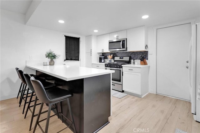 21046 Lone Eagle Rd, Apple Valley, CA 92308 - kitchen featuring appliances with stainless steel finishes, a kitchen bar, light wood-style flooring, a peninsula, and white cabinets