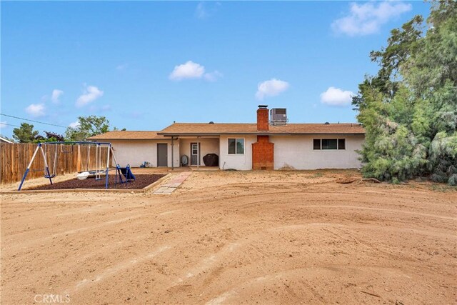 21046 Lone Eagle Rd, Apple Valley, CA 92308 - back of house featuring a playground, a chimney, fence, and stucco siding