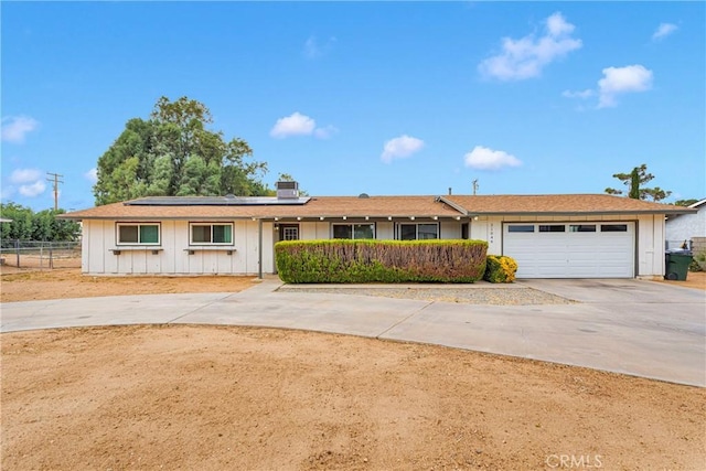 21046 Lone Eagle Rd, Apple Valley, CA 92308 - ranch-style house with board and batten siding, concrete driveway, solar panels, fence, and an attached garage