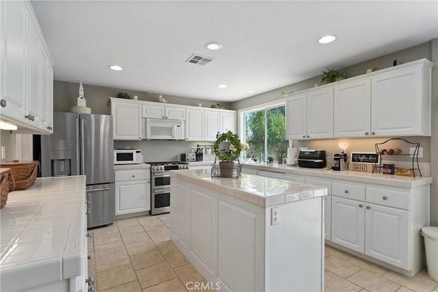 5549 Pine Ave, Chino Hills, CA 91709 - kitchen featuring stainless steel appliances, tile countertops, white cabinetry, a center island, and recessed lighting