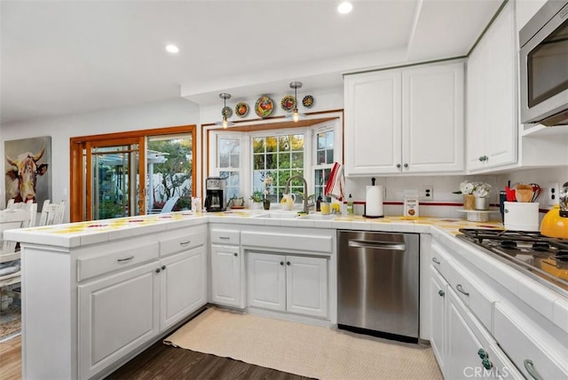 21372 Sand Dollar Ln, Huntington Beach, CA 92646 - kitchen with stainless steel appliances, a sink, white cabinetry, tile countertops, and a peninsula