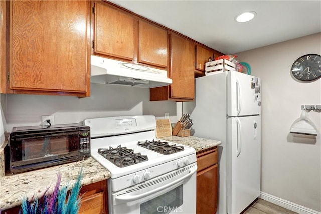 1118 Valencia St Unit 216, Los Angeles, CA 90015 - kitchen with white appliances, under cabinet range hood, brown cabinets, baseboards, and recessed lighting