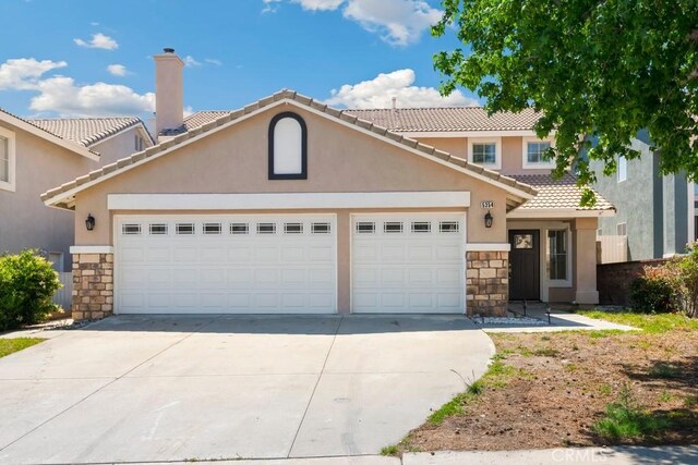 5354 Wrangler Dr, Fontana, CA 92336 - view of front facade with stone siding, an attached garage, driveway, and a tiled roof