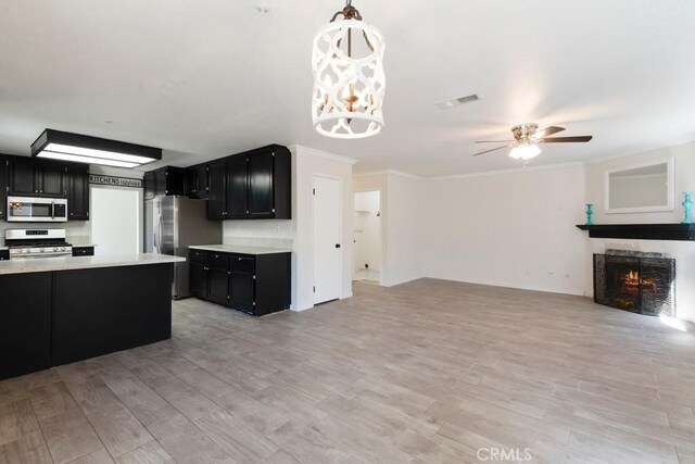 5354 Wrangler Dr, Fontana, CA 92336 - kitchen featuring dark cabinetry, stainless steel appliances, open floor plan, light countertops, and ornamental molding