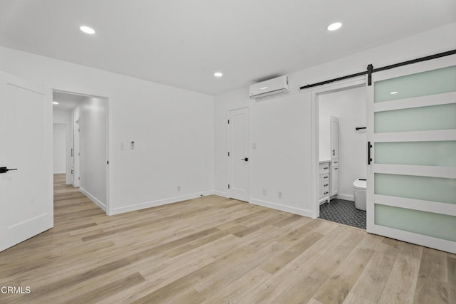 6721 S Springpark Ave Unit 3A, Los Angeles, CA 90056 - unfurnished bedroom featuring a wall unit AC, a barn door, light wood finished floors, recessed lighting, and connected bathroom