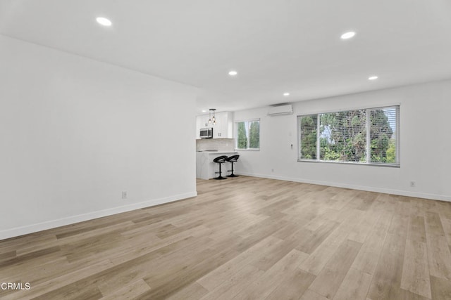 6721 S Springpark Ave Unit 3A, Los Angeles, CA 90056 - unfurnished living room featuring an AC wall unit, recessed lighting, light wood-style flooring, and baseboards