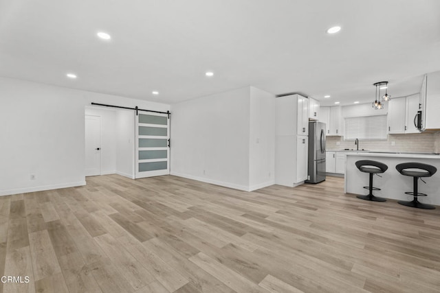 6721 S Springpark Ave Unit 3A, Los Angeles, CA 90056 - unfurnished living room with a sink, a barn door, light wood-style floors, recessed lighting, and baseboards