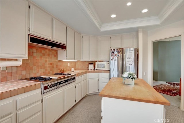 3511 Daffodil Ave Unit 14, Corona Del Mar, CA 92625 - kitchen with stainless steel appliances, ornamental molding, under cabinet range hood, a raised ceiling, and a kitchen island