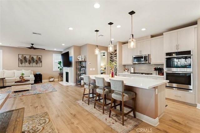 32106 Richardson St, Menifee, CA 92584 - kitchen featuring stainless steel appliances, open floor plan, a center island with sink, light wood-type flooring, and recessed lighting