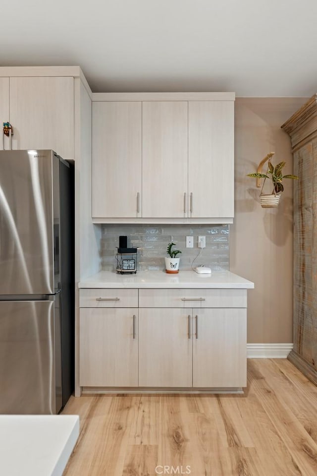 32106 Richardson St, Menifee, CA 92584 - kitchen with freestanding refrigerator, light countertops, light wood-type flooring, backsplash, and baseboards