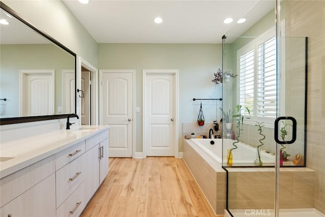 32106 Richardson St, Menifee, CA 92584 - bathroom featuring wood finished floors, a bath, double vanity, a stall shower, and recessed lighting