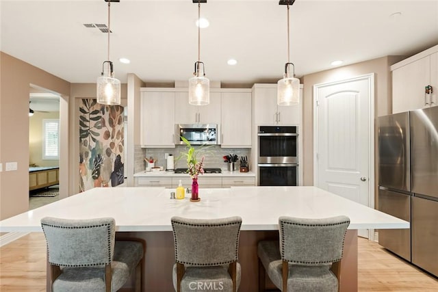 32106 Richardson St, Menifee, CA 92584 - kitchen featuring appliances with stainless steel finishes, decorative backsplash, a kitchen bar, light countertops, and recessed lighting