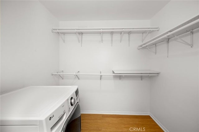 walk in closet with washer and clothes dryer and light wood-style flooring