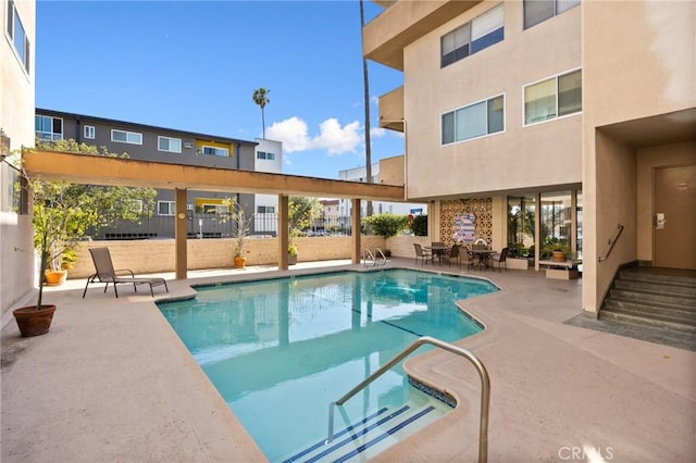 community pool with a patio area and fence