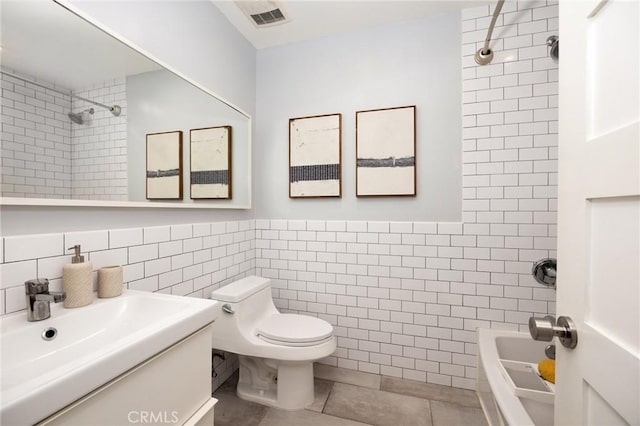 bathroom featuring tile walls, tile patterned flooring, toilet, shower / washtub combination, and vanity