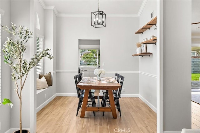 dining area featuring light wood-type flooring, ornamental molding, baseboards, and a chandelier