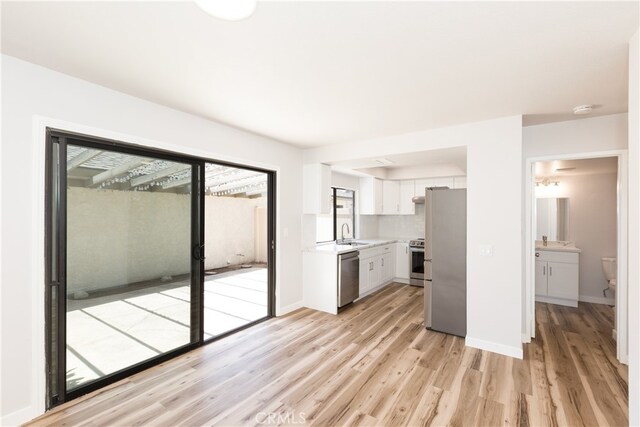 1485 W Cerritos Ave Unit 8, Anaheim, CA 92802 - kitchen featuring appliances with stainless steel finishes, light countertops, white cabinets, and light wood-style flooring
