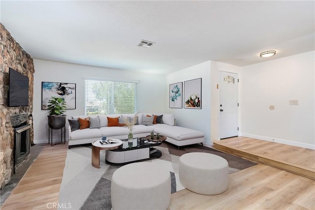 16230 Rodeo St, Hesperia, CA 92345 - living area featuring light wood-type flooring, a stone fireplace, and baseboards