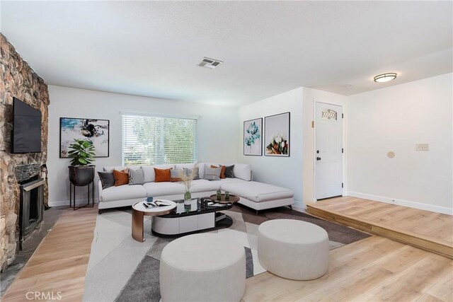 16230 Rodeo St, Hesperia, CA 92345 - living area featuring light wood-style flooring, a stone fireplace, and baseboards