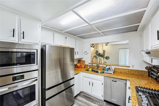kitchen featuring appliances with stainless steel finishes, a sink, white cabinetry, light countertops, and light wood-type flooring