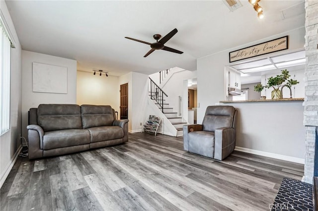 living room with wood finished floors, baseboards, ceiling fan, and stairway