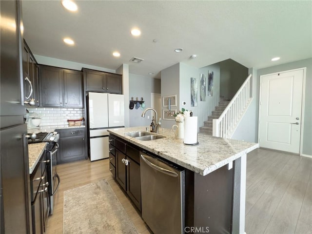 5485 San Roberto, San Diego, CA 92154 - kitchen with appliances with stainless steel finishes, a sink, dark brown cabinetry, light wood-type flooring, and decorative backsplash
