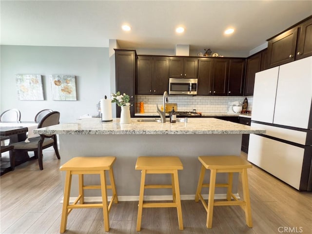 5485 San Roberto, San Diego, CA 92154 - kitchen with freestanding refrigerator, stainless steel microwave, a sink, dark brown cabinets, and light wood-style floors