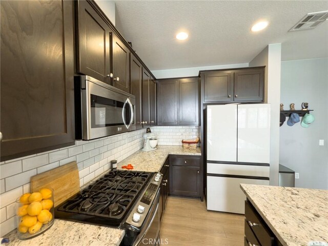 5485 San Roberto, San Diego, CA 92154 - kitchen with stainless steel microwave, black gas range oven, freestanding refrigerator, dark brown cabinetry, and light wood-style floors