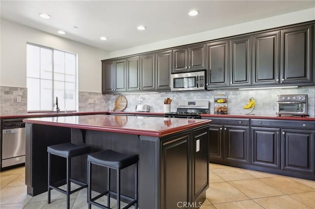 8519 E Kendra Loop, Orange, CA 92867 - kitchen featuring stainless steel appliances, a sink, a kitchen island, light tile patterned floors, and a kitchen breakfast bar