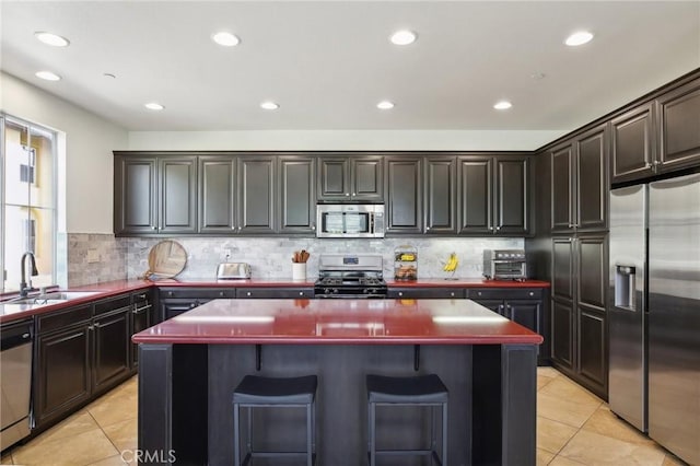 8519 E Kendra Loop, Orange, CA 92867 - kitchen with appliances with stainless steel finishes, a sink, a kitchen island, light tile patterned floors, and tasteful backsplash