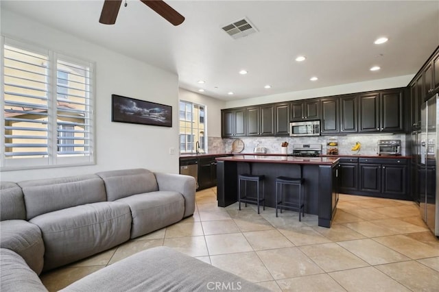 8519 E Kendra Loop, Orange, CA 92867 - kitchen featuring appliances with stainless steel finishes, open floor plan, decorative backsplash, light tile patterned floors, and a center island