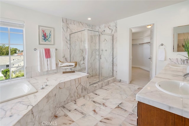 full bathroom with a marble finish shower, a bath, a walk in closet, double vanity, and baseboards